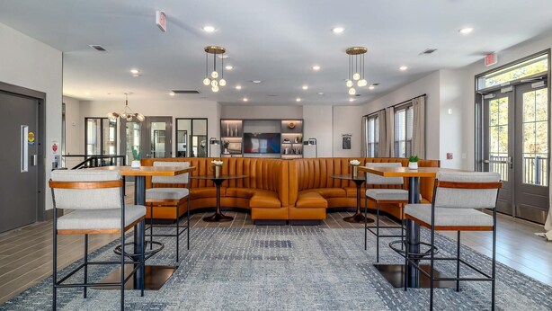 A modern hotel lobby with a central seating area, multiple tables, and a large rug. - Landing | Modern 1BD, Clubhouse, Gym (Charlotte)