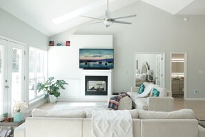Ein Wohnzimmer mit Kamin, Deckenventilator und großem Fenster.