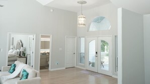 A spacious living room with a high ceiling, a large window, and a dining area. - Bayfront Retreat on 1.5 Acres - Private Dock - 4BR Near Destin (Freeport)