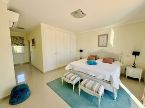 Ein Schlafzimmer mit einem Bett, zwei Nachttischen, einer Bank, einem Kleiderschrank und einem Fenster.