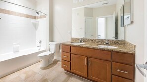 A bathroom with a bathtub, toilet, vanity with a sink, and a large mirror. - Landing | Spectacular 1BD, Pool, Courtyard (Hyattsville)