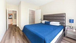 A bedroom with a bed, bedside table, and a lamp. - Landing | Spectacular 1BD, Pool, Courtyard (Hyattsville)