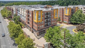 Um edifício de apartamentos moderno com várias andares, com varandas e uma fachada de tijolo e cor amarela.