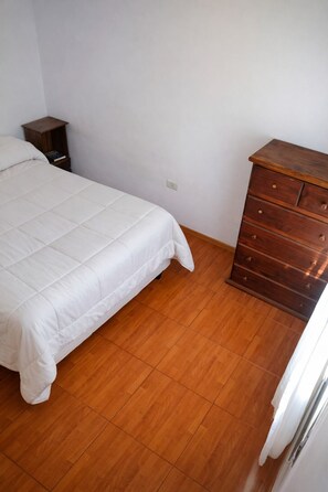 Une chambre à coucher avec un lit, une commode en bois et une table de chevet.