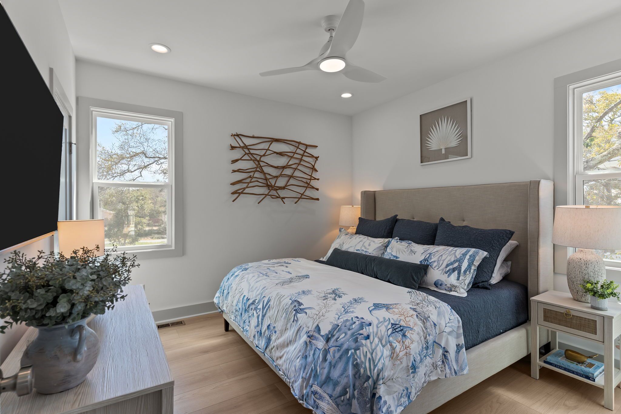 A bedroom with a bed, bedside tables, a ceiling fan, and a window.