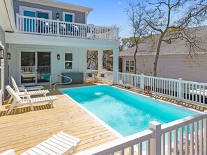 A two-story house with a swimming pool, deck chairs, and a hot tub. - Sacred Tides: Spacious 6BR Luxury Rental w/ Pri Pool & Elevator, Near Beach! (Oak Island)
