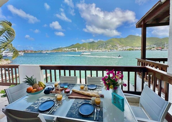 A table set for breakfast with a view of the sea and mountains.