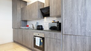 Een moderne keuken met grijze kastjes, een ingebouwde magnetron en een roestvrijstalen oven.
