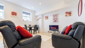 Een moderne woonkamer met leren fauteuils, een eethoek en een flatscreen televisie waarop 'NETFLIX' wordt afgespeeld.