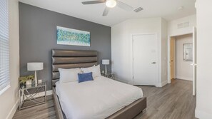 A bedroom with a bed, a ceiling fan, a painting, a door, and a nightstand. - Landing | Modern 1BD, Gym, Pool (Tampa)