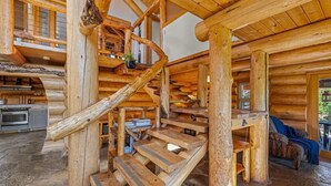 Ein Blockhaus-Interieur mit Wendeltreppe, Steinböden und einer Küchenzeile.