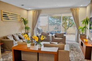 A living room with a sofa, coffee table, and potted plants. - Orlando Retreat | 4BR Townhome • 8 Min to Disney (Osceola County)