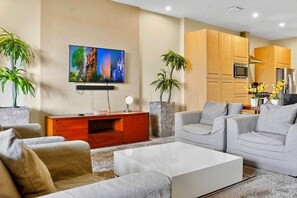 A modern living room with a flat-screen TV, grey sofas, a white coffee table, and a wooden entertainment unit. - Orlando Retreat | 4BR Townhome • 8 Min to Disney (Osceola County)