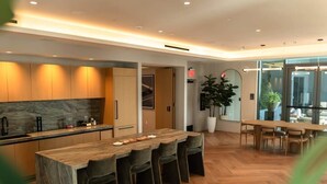 A modern kitchen with a central island, bar stools, and a dining table with chairs. - The Skyline Luxe Suite | 1BR+Den Downtown Miami (Miami)