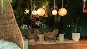 A cozy lounge area with wicker chairs, a small round table, hanging paper lanterns, and a large potted plant. - The Skyline Luxe Suite | 1BR+Den Downtown Miami (Miami)