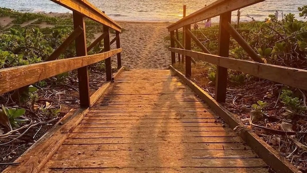 A wooden boardwalk leading to the beach with a sunset in the background. - Cozy condo with a view of famous Kamaole Beach II (Kihei)