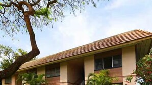 A two-story building with a tiled roof, a central staircase, and a well-maintained lawn. - Cozy condo with a view of famous Kamaole Beach II (Kihei)