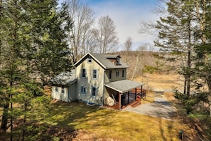 A two-story house with a porch, surrounded by trees. - Hunter Mountain Home with Fire Pit & Deck (Hunter)