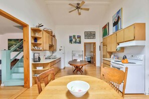 A compact kitchen with wooden cabinets, a dining table, and a stove. - Hunter Mountain Home with Fire Pit & Deck (Hunter)