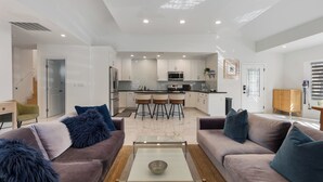 Een moderne woonkamer met een bank, salontafel en een keuken op de achtergrond.