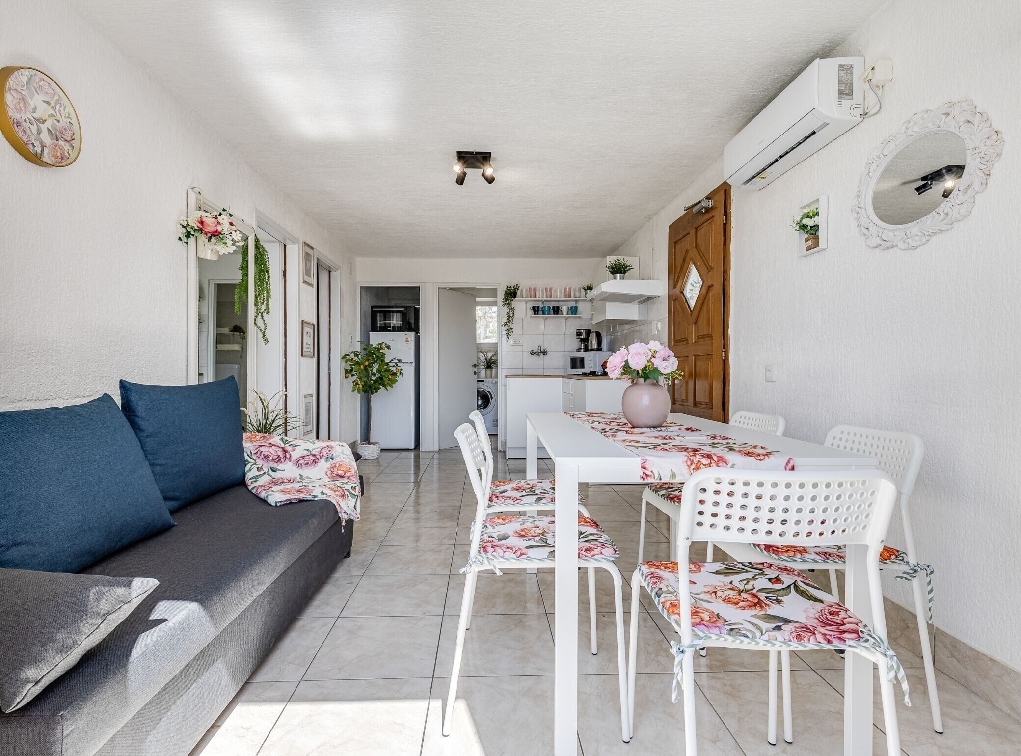 Un espacio habitable compacto con sofá, mesa de comedor, sillas y una zona de cocina.