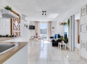 Eine moderne Wohnung mit Küche, Essbereich und Wohnzimmer, ausgestattet mit einem Fernseher, einer Couch und einem Balkon mit Blick.