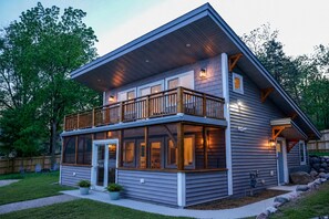 Une maison à deux étages avec un balcon, de grandes fenêtres et une porte d’entrée.