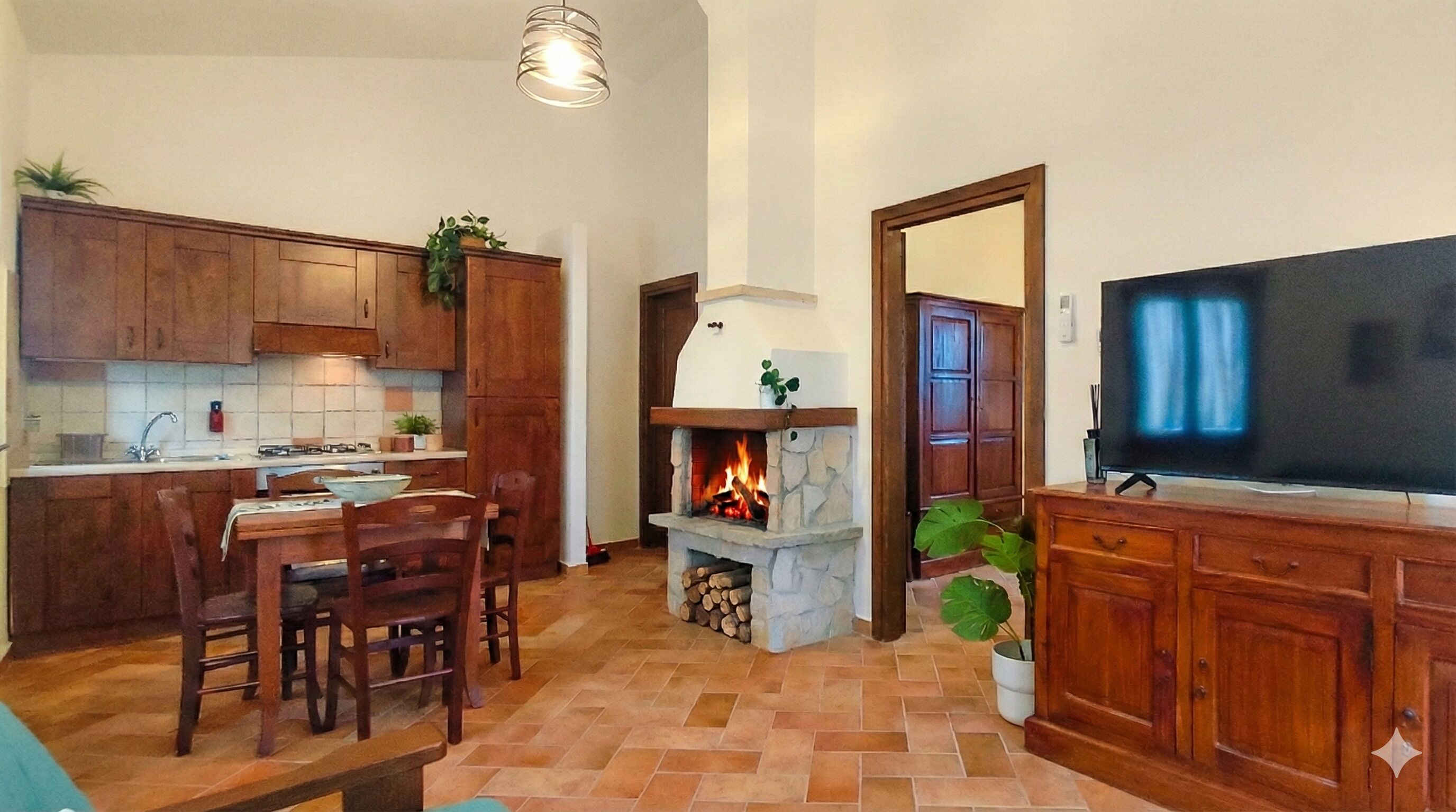 Eine Küche mit Holzausstattung, einem Esstisch mit Stühlen, einem Kamin und einem Fernseher im Wohnbereich.