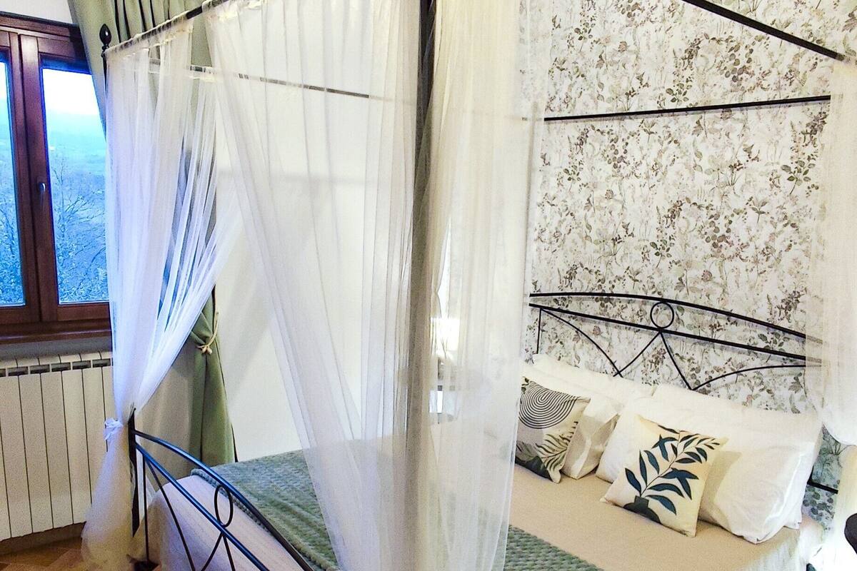 A bed with a metal frame, a green bedspread, and patterned pillows.