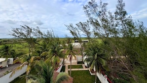 Um resort tropical com palmeiras, um edifício branco e vista para o oceano.