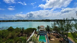 Vista de uma praia com piscina, um gazebo e céu claro.
