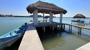 Um cais com uma estrutura de telhado de palha, um barco pequeno e água calma.
