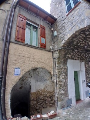 A narrow alleyway with a stone archway, a wooden door with a green frame, and a window with wooden shutters. - Elegant Bajardo Apartment With Stunning Views (Bajardo)