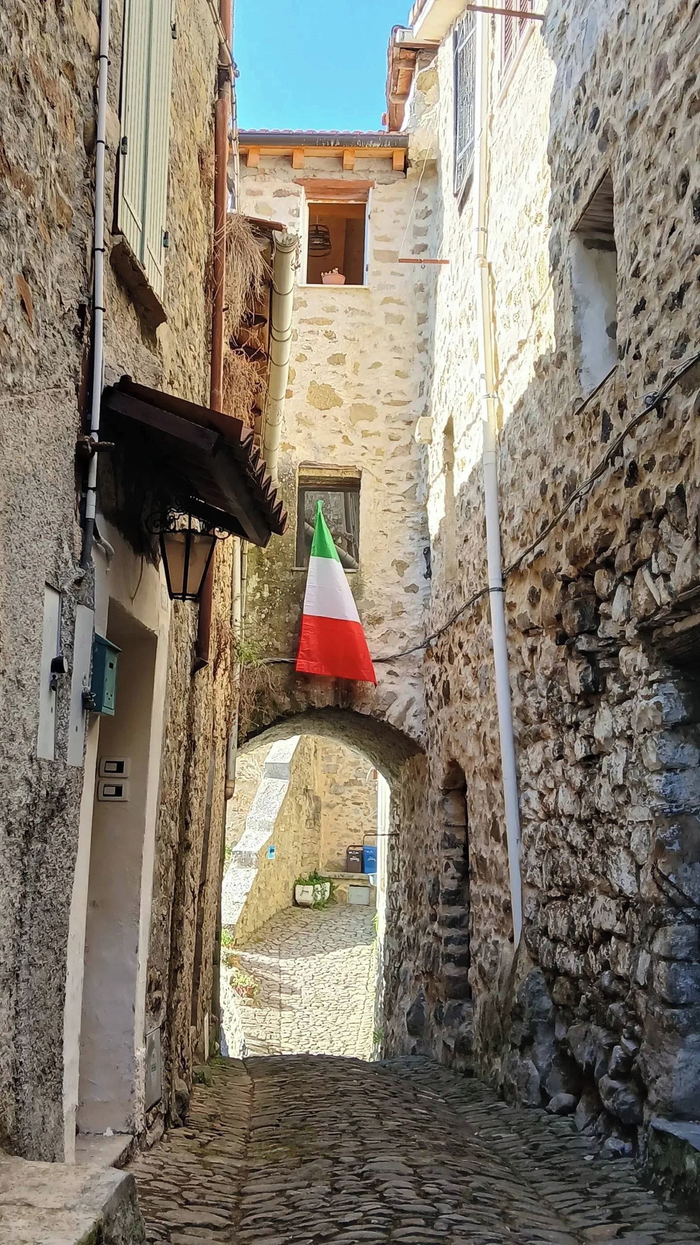 Un estrecho callejón empedrado con una bandera colgada de un edificio.