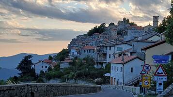 A hillside village with buildings, a winding road, and various road signs.