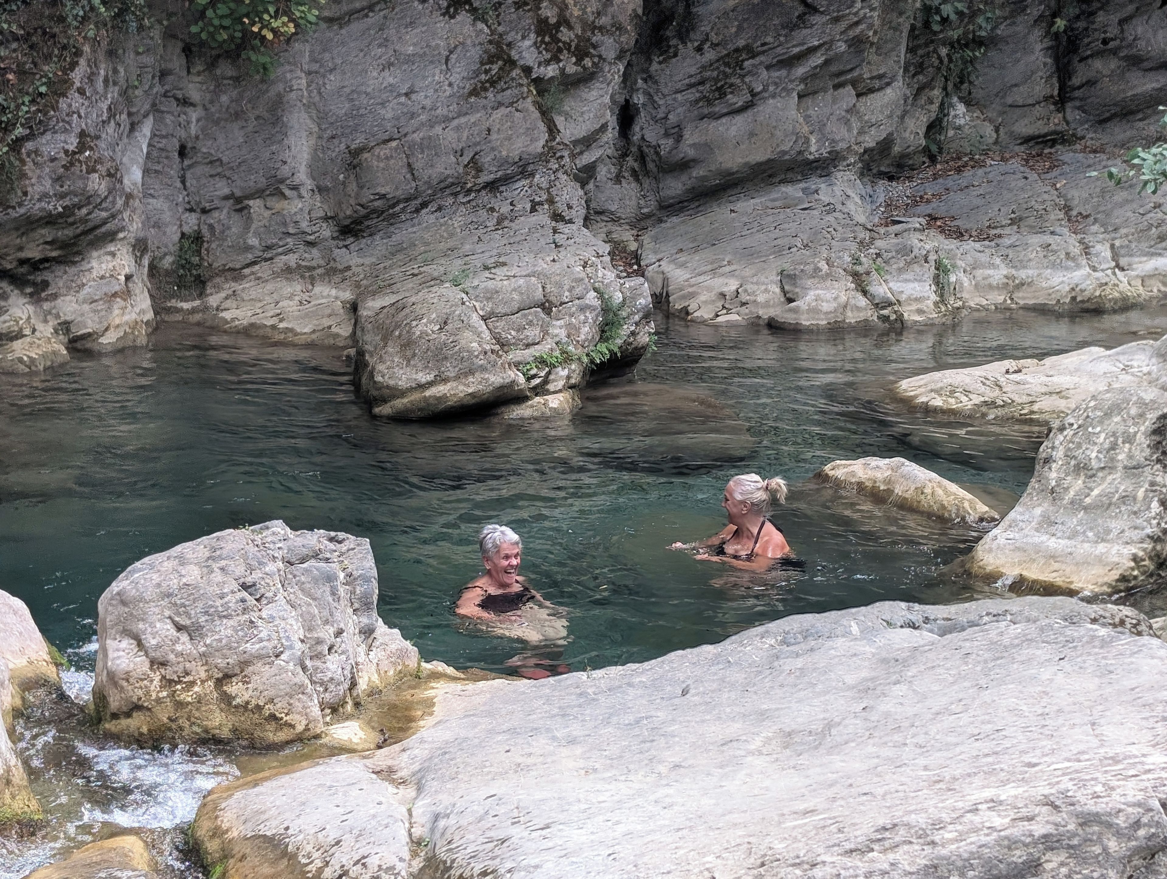 Un corpo d'acqua naturale con terreno roccioso e grandi massi.