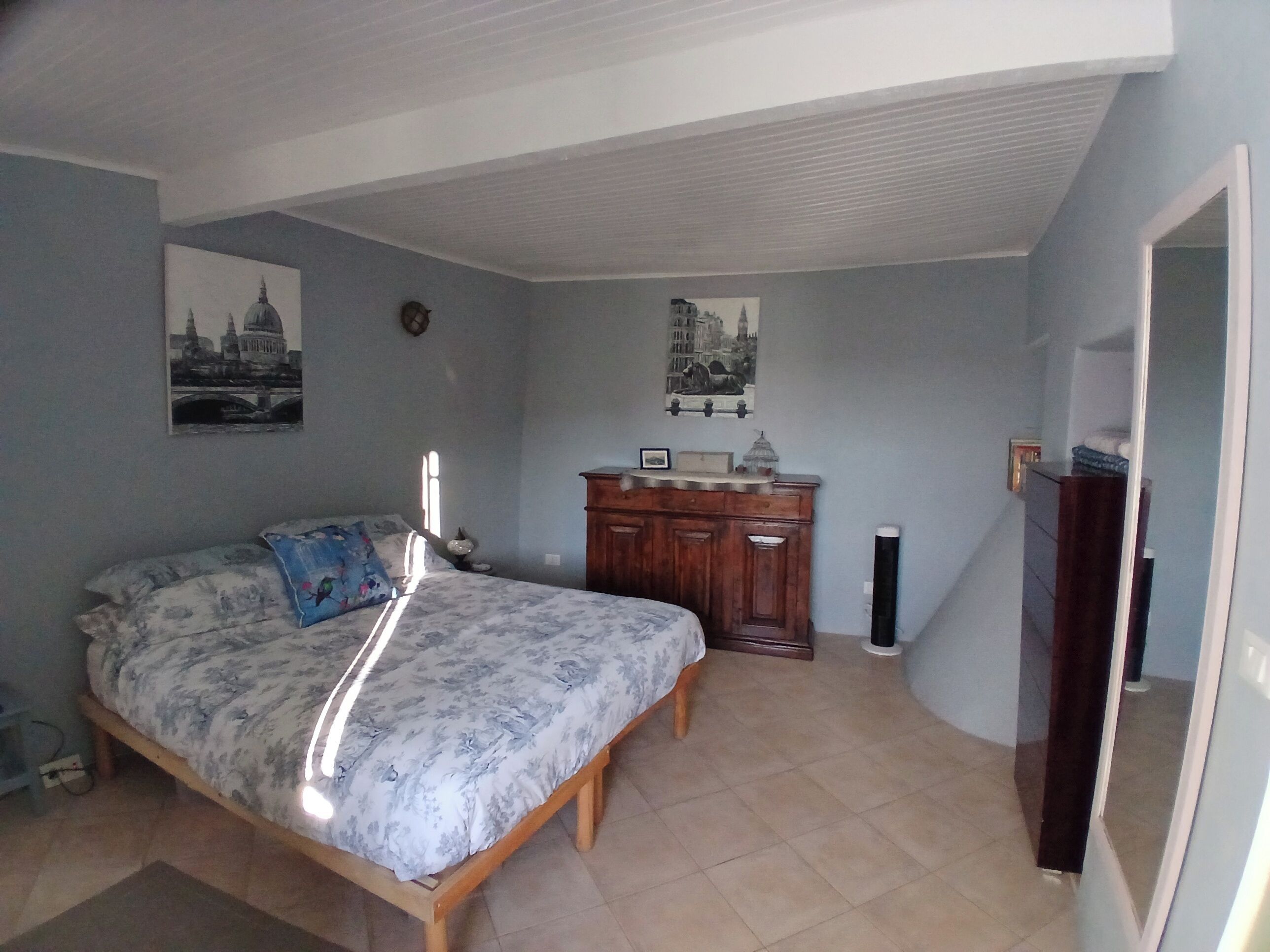 A bedroom with a bed, a dresser, and two wall-mounted pictures.
