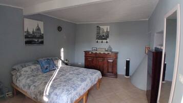 A bedroom with a bed, a dresser, and two wall-mounted pictures.