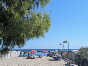 Una playa con sombrillas, gente y cielo despejado.