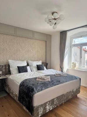 A bedroom with a bed, a nightstand, a window, and a ceiling light fixture.