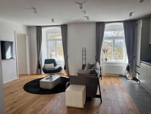 A modern living room with a sofa, a chair, a coffee table, and a TV.