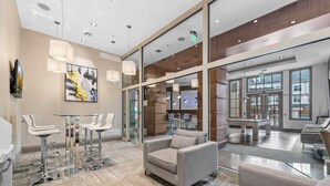 Eine moderne Lobby mit Sitzbereichen, einem Billardtisch und großen Fenstern.