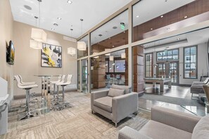 Eine moderne Lobby mit Sitzbereichen, einem Billardtisch und großen Fenstern.