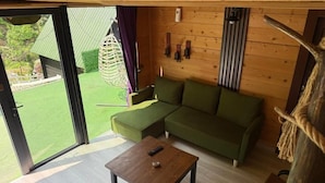 A wooden interior with a green sofa, a wooden table, and a hanging chair. - Ayder Dağ Evleri Elizan (Camlihemsin)