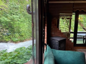 Une pièce avec vue sur une rivière, une cheminée en briques et un canapé vert.