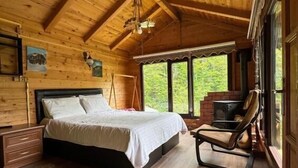 A wooden cabin bedroom with a bed, a chair, and a fireplace. - Ayder Dağ Evleri Elizan (Camlihemsin)