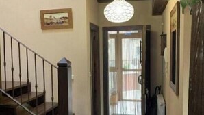 A staircase with wooden railings, a tiled floor, a hanging light fixture, and a door leading to an outdoor area. - El Acebo de Tanarro (Sepúlveda)