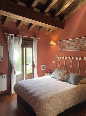 Um quarto com cama, cortinas, luminária na parede e janela.