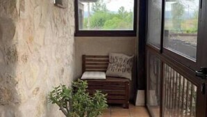 A small, enclosed porch with a potted plant, a bench, and a view of the outdoors. - El Acebo de Tanarro (Sepúlveda)