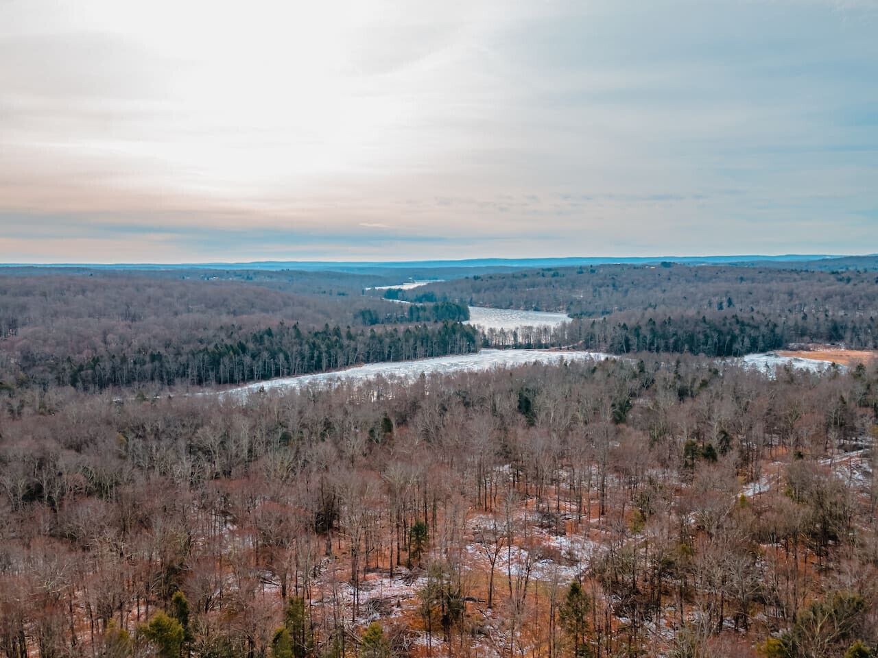A panoramic view of a forested landscape with a river and distant hills.